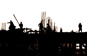 Silhouette of workers at an industrial construction and erection site.