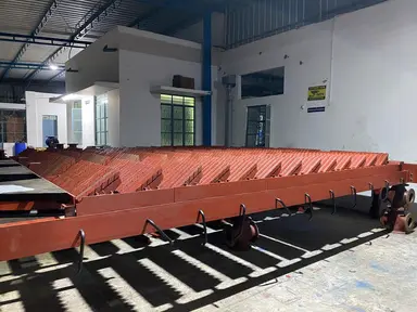 Fabricated mechanical dumping grate structure inside an industrial workshop.