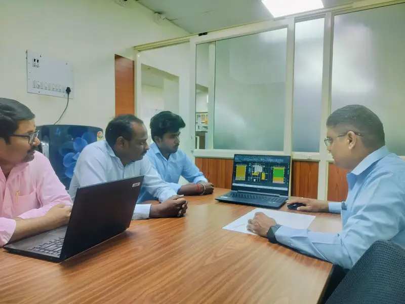 Engineers reviewing a piping flexibility simulation on a laptop during a meeting.